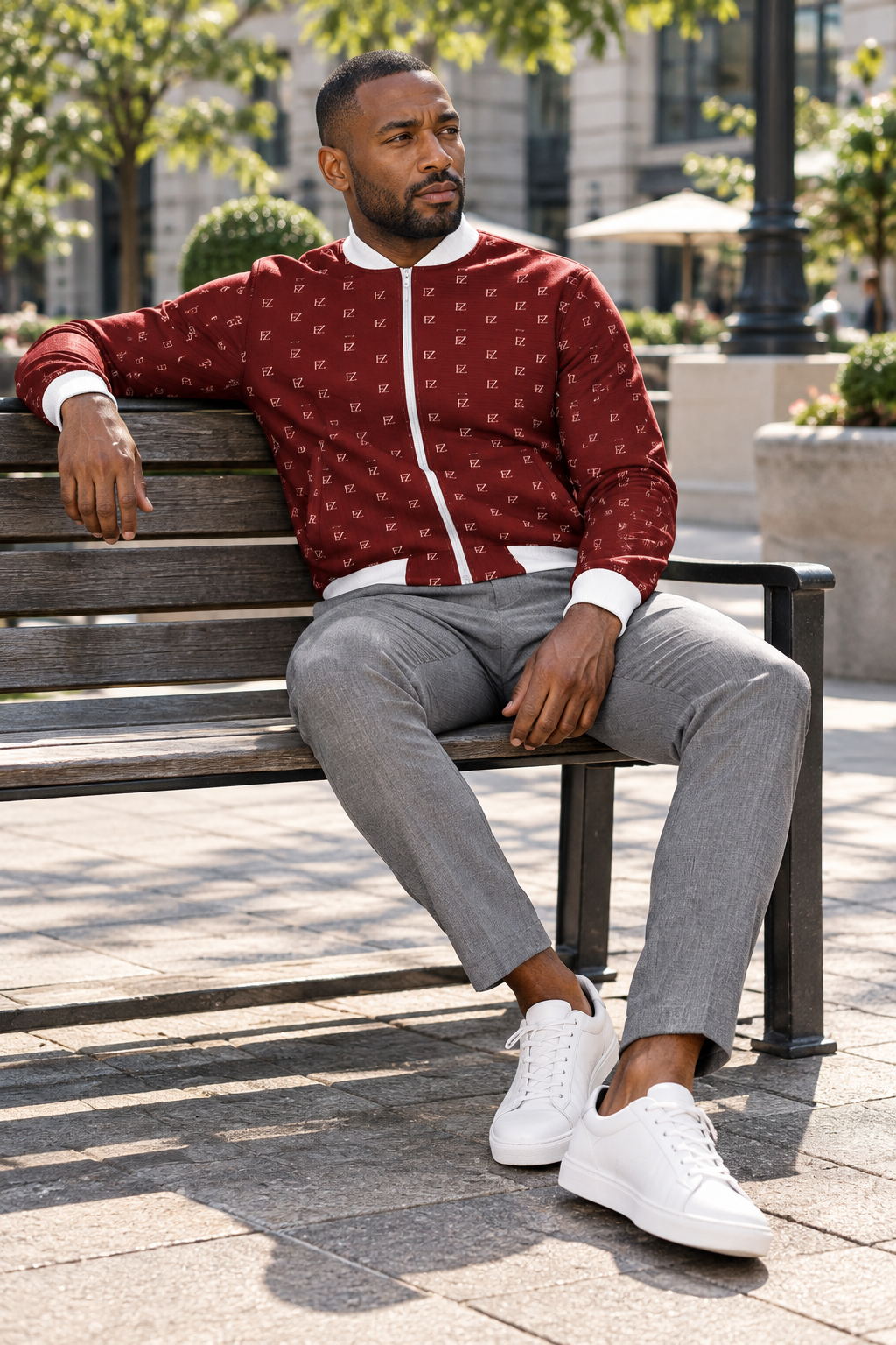 Black man in the burgundy FZ bomber on a city plaza bench