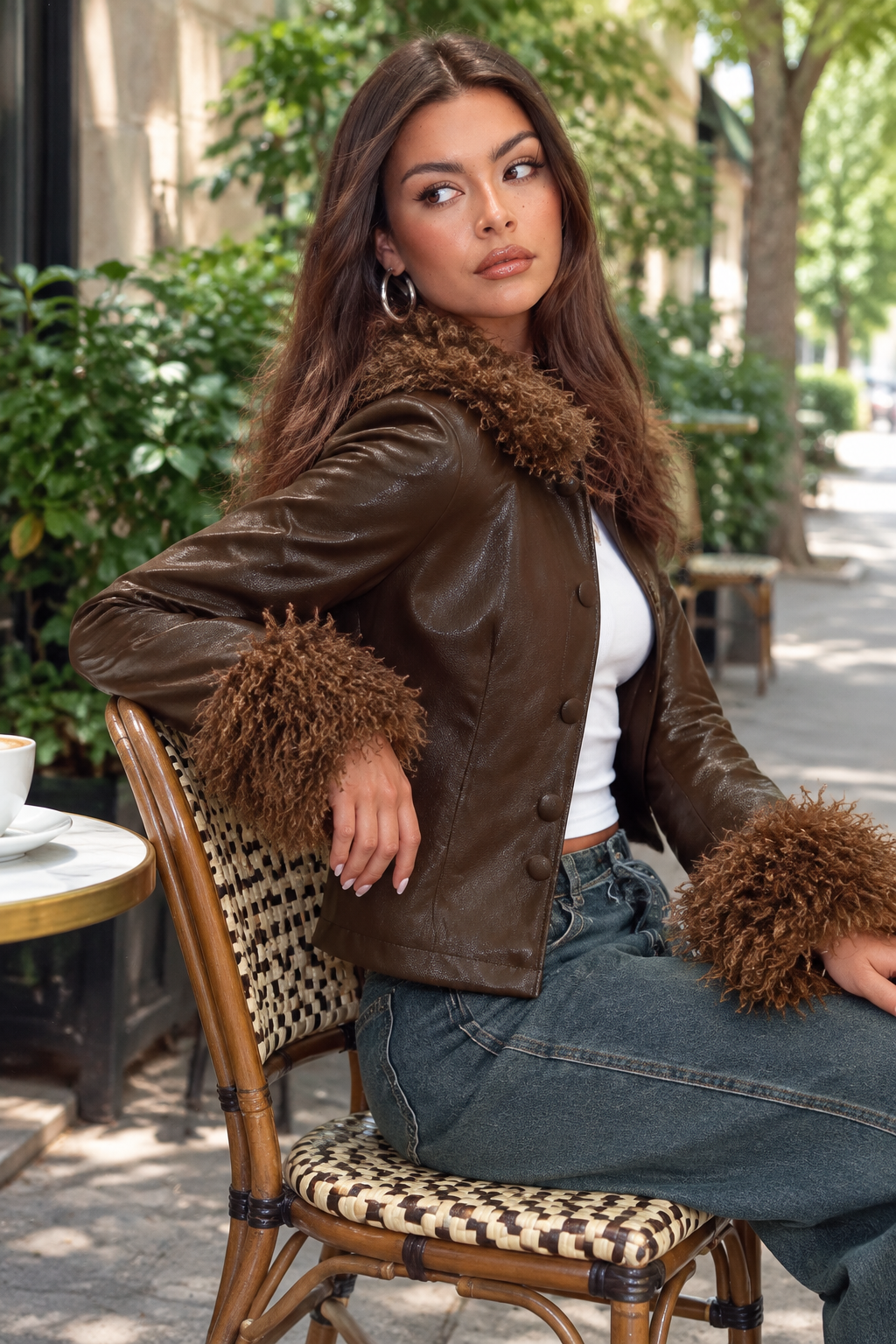 Latina model seated at an outdoor café in the PU jacket