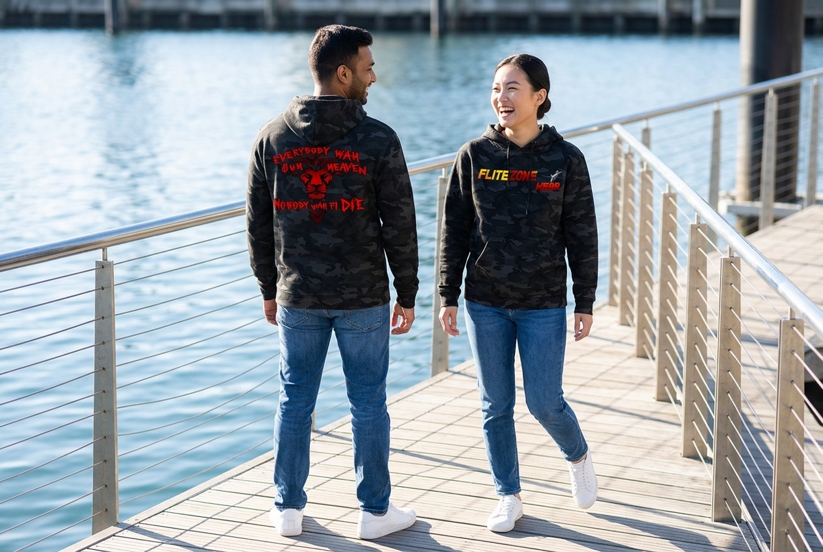 Playful waterfront shot of an East Asian woman showing the black-camo hoodie front and a South Asian man showing the back